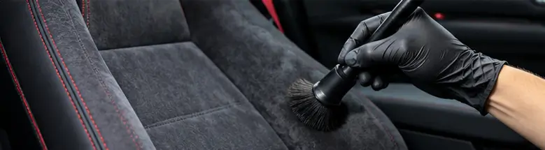 Cleaning premium Alcantara car seats with a soft brush and microfiber cloth.
